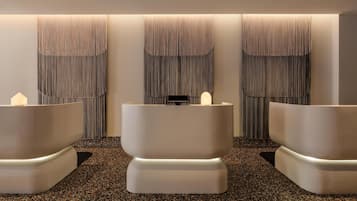 Um espaço de spa com três grandes banheiras curvas e brancas e um balcão de atendimento.