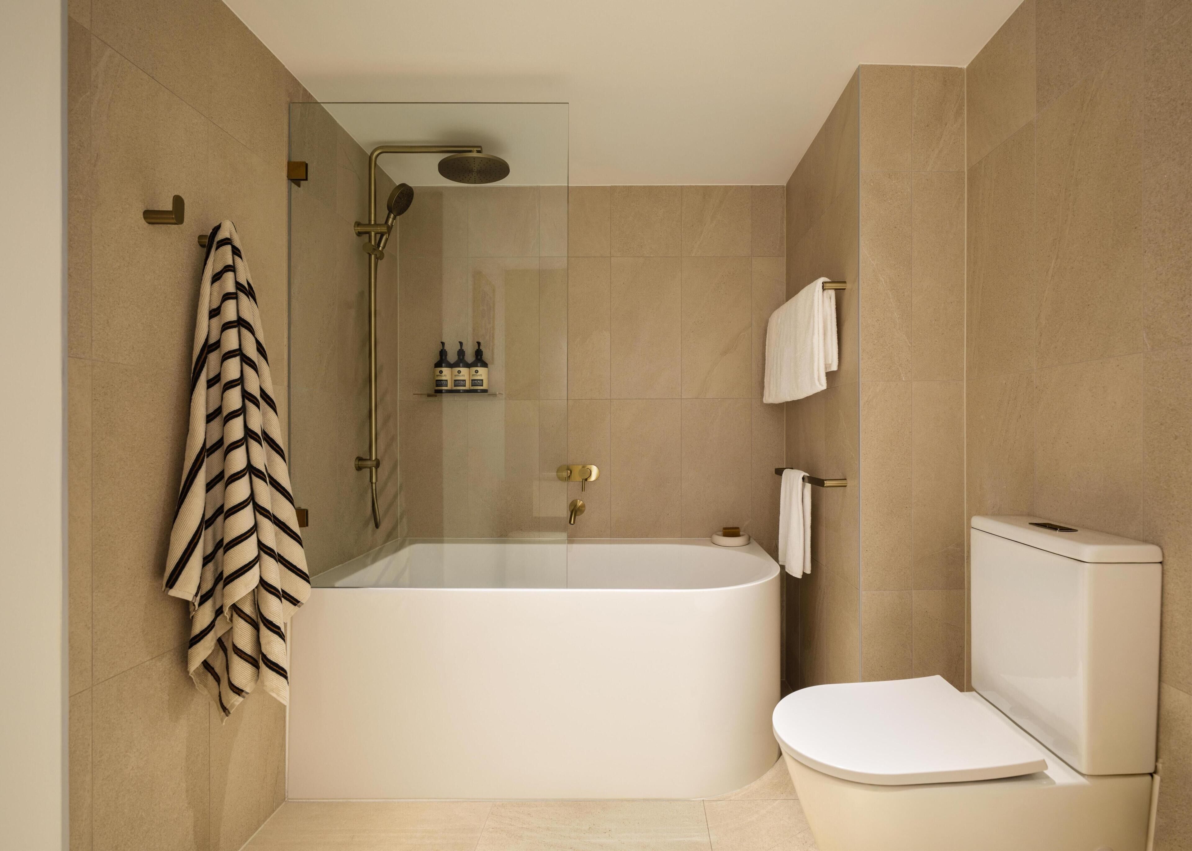 A modern bathroom with a freestanding bathtub, a toilet, and a glass-enclosed shower area.