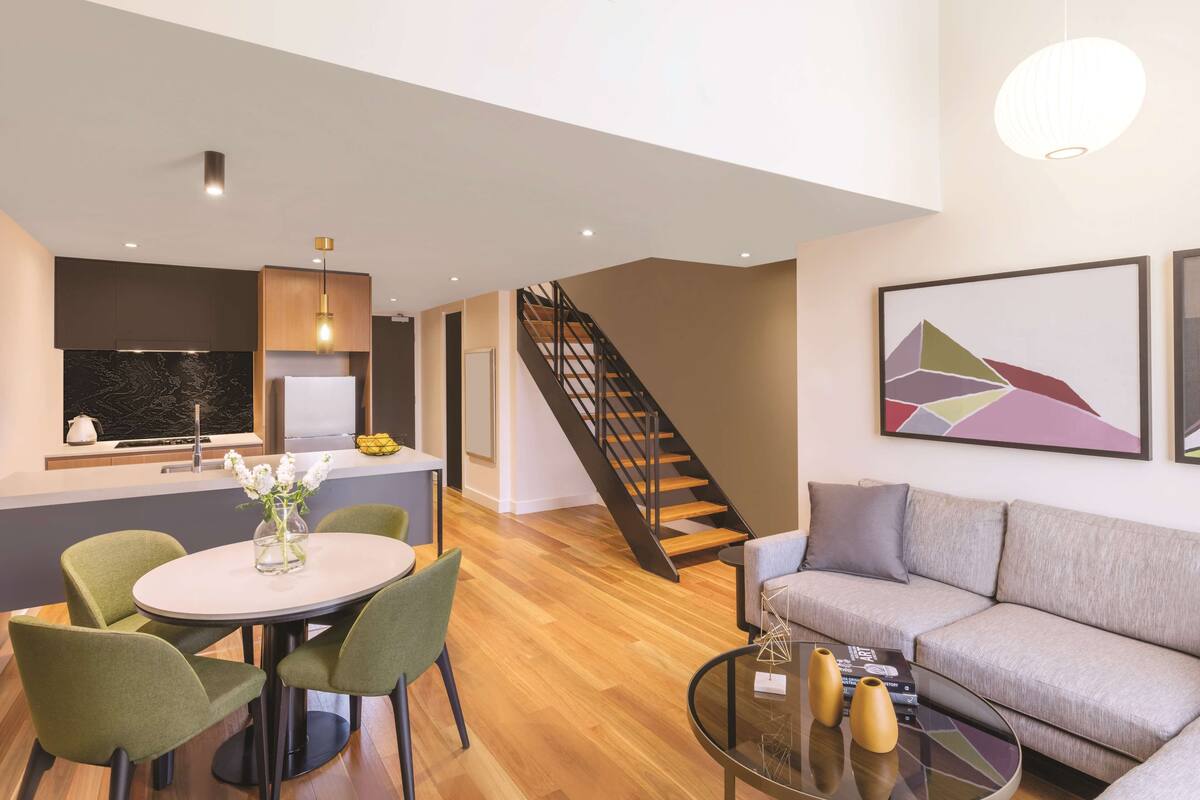 A modern living room with a sofa, a coffee table, and a dining area with chairs and a table.
