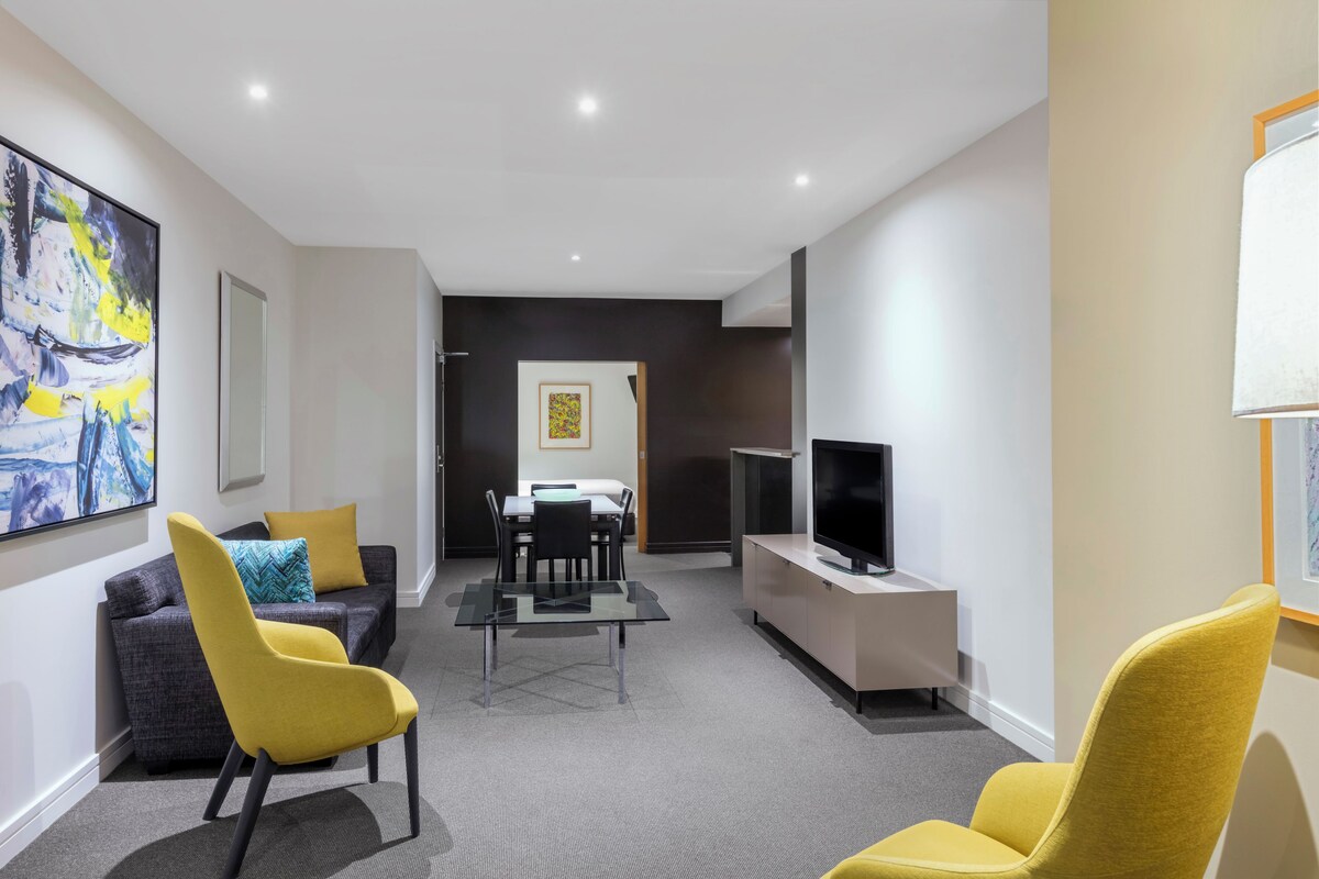 Una sala moderna con sofá, sillones, una mesa de comedor y televisor.