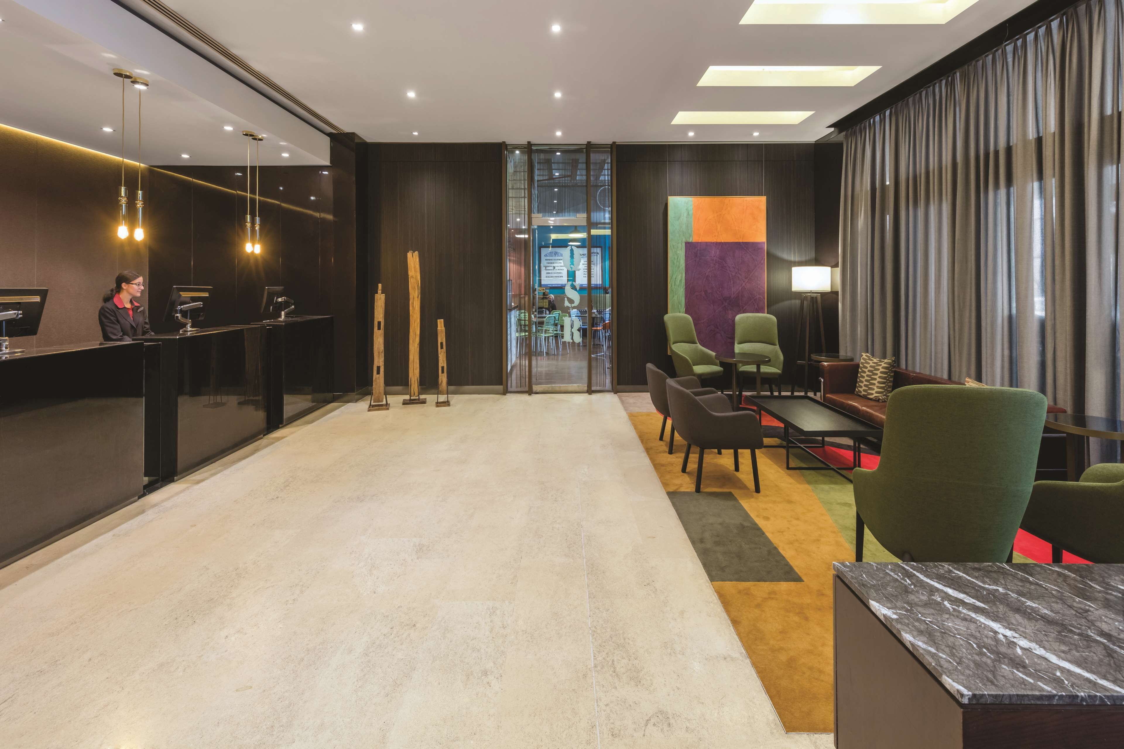 A modern reception area with a reception desk, seating area, and a view into the lobby.