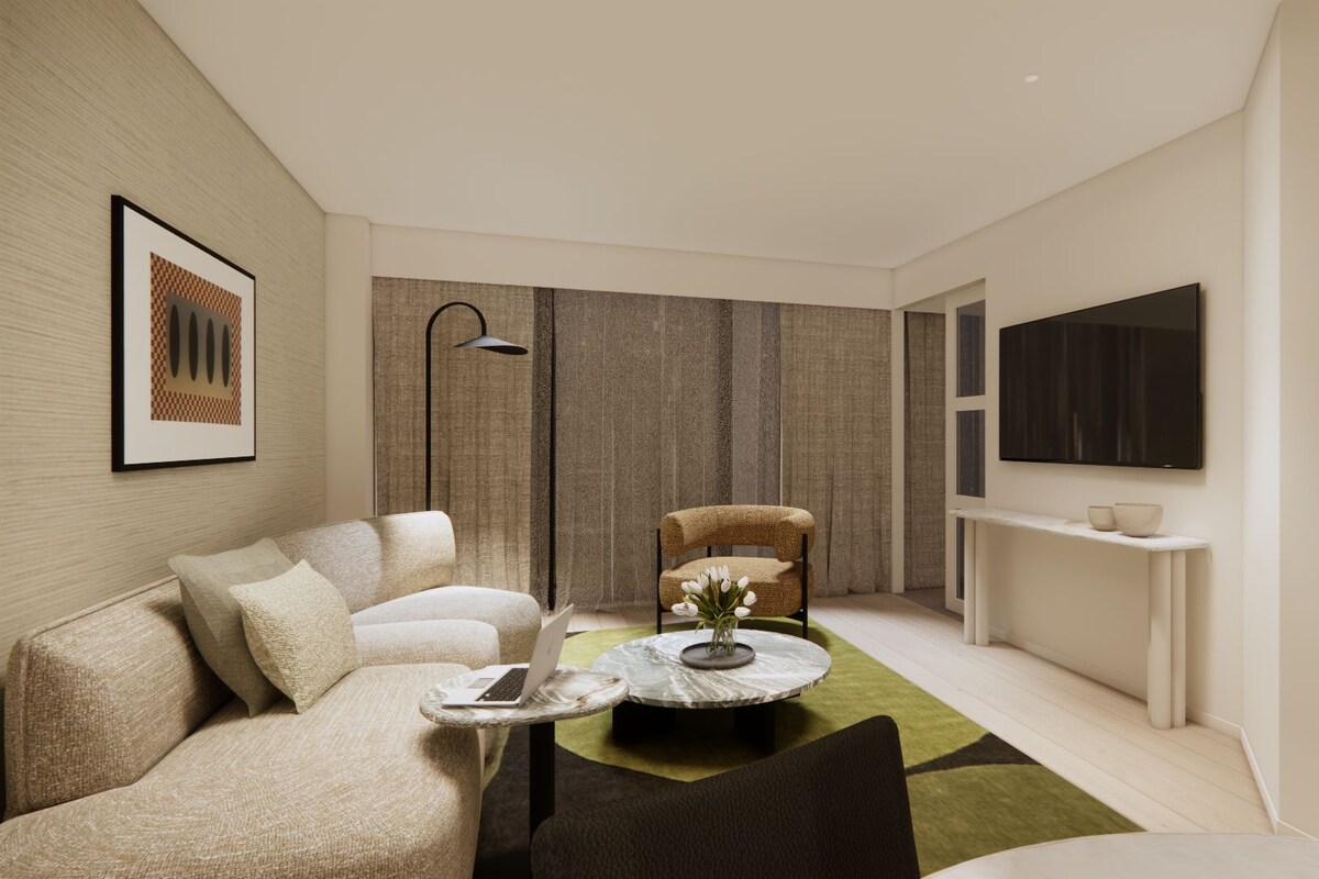 Una sala moderna con un sofá, una mesa redonda de centro, una silla, una lámpara de pie, un televisor y un mueble bajo con objetos decorativos.