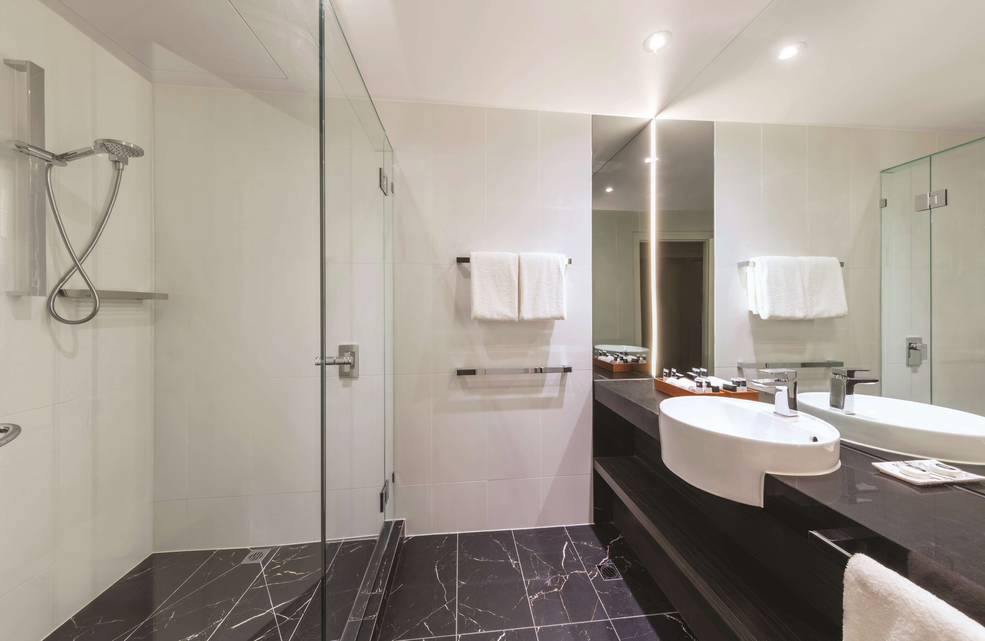 A modern bathroom with a glass-enclosed shower, two sinks, and a large mirror.
