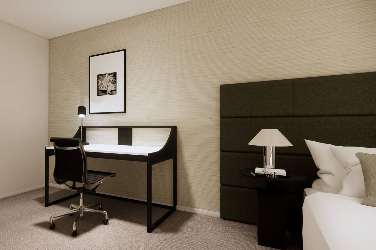 A hotel room with a desk, chair, lamp, and bed.