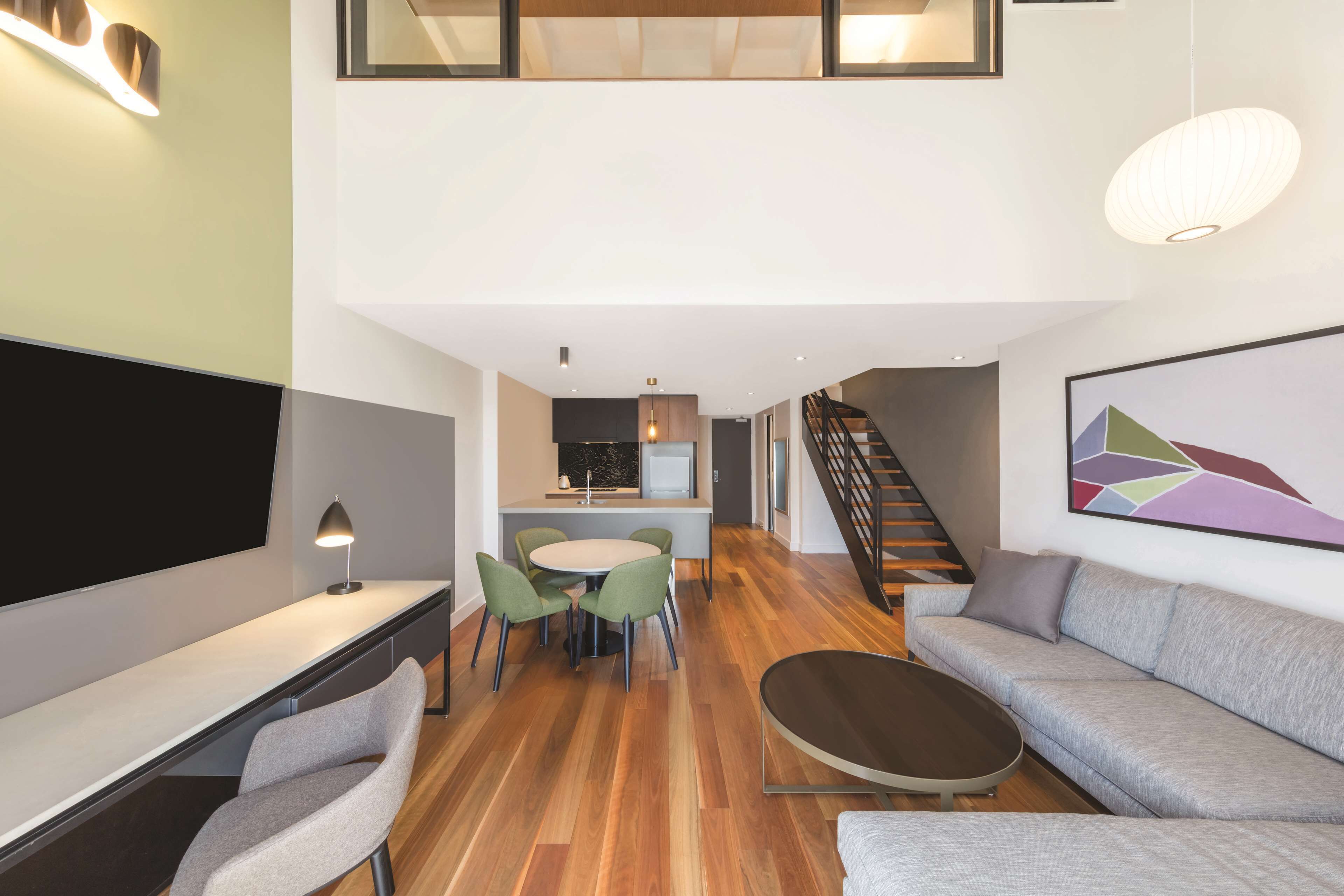 A modern interior with a dining area, a sofa, and a staircase.
