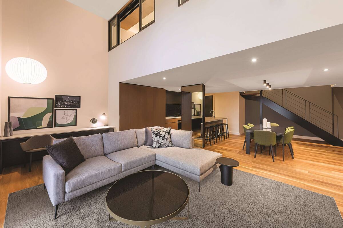 A modern living room with a sectional sofa, a round coffee table, and a dining area with a table and chairs.