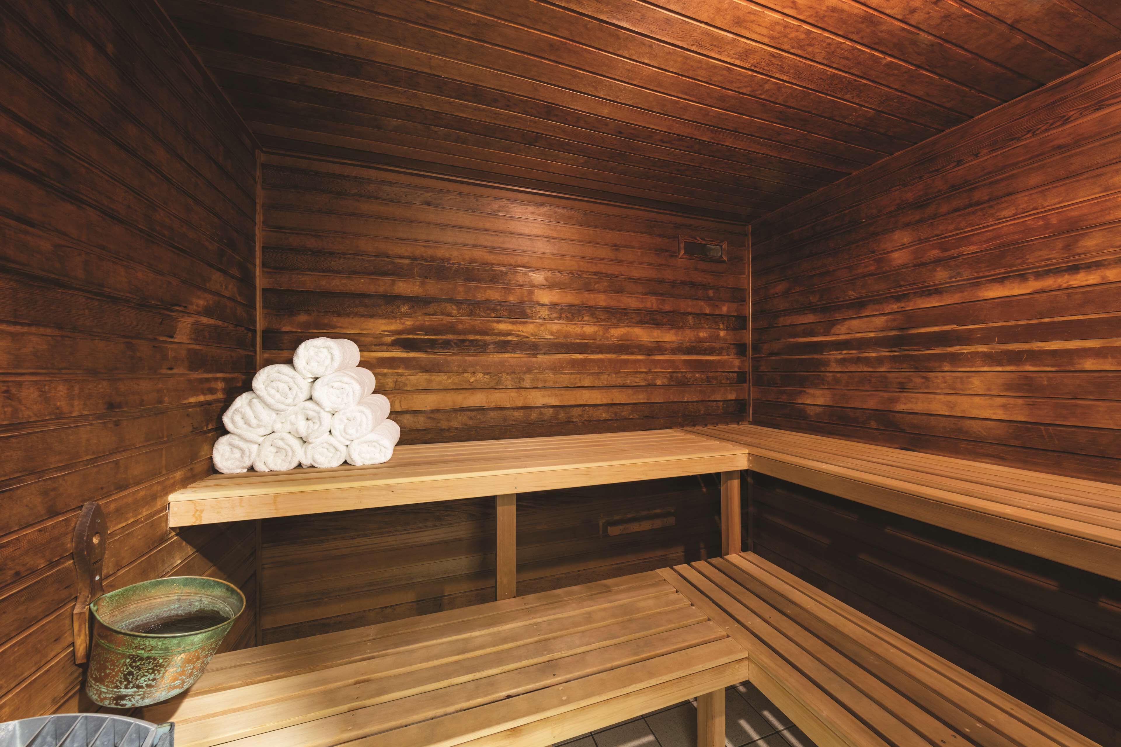 A sauna with wooden benches and a stack of towels.