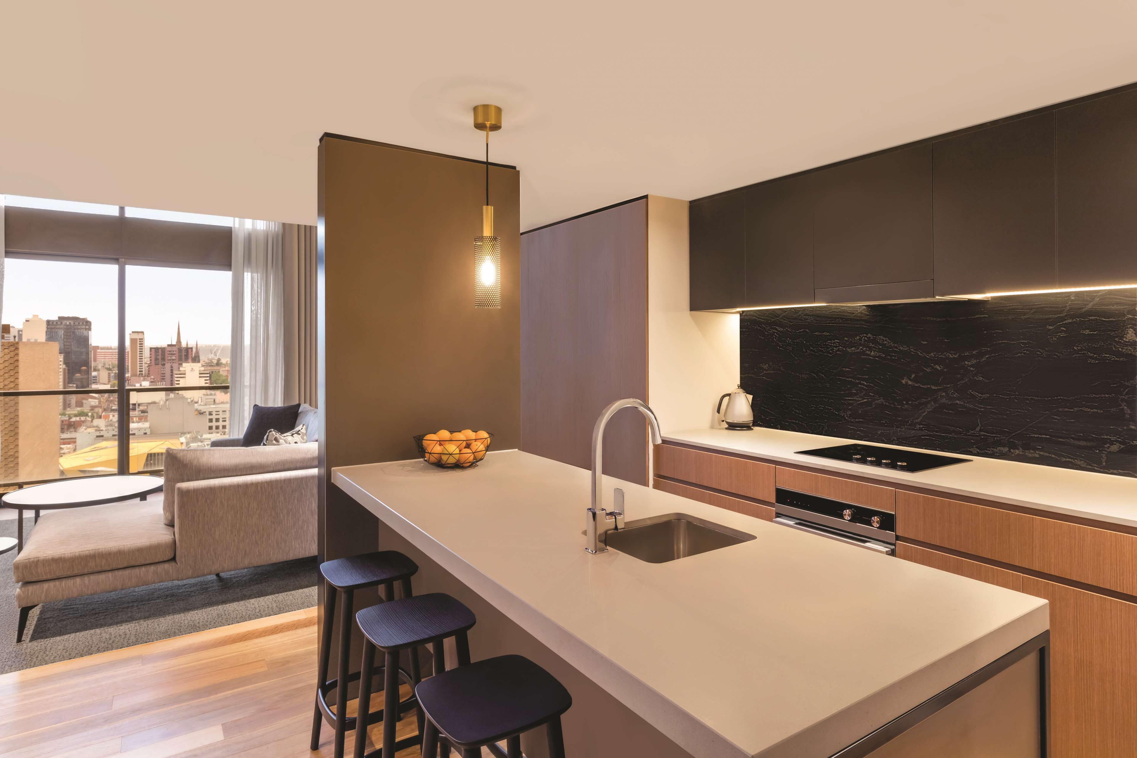 A modern kitchen with a large island, bar stools, and a city view.