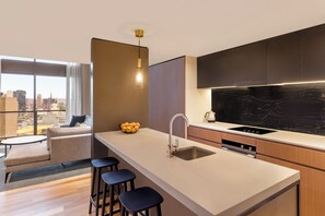 Cocina moderna con una isla grande, taburetes de bar, horno empotrado y vista a la ciudad a través de la ventana.