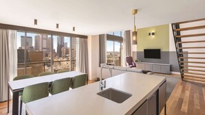 Une cuisine moderne dotée d’un grand îlot central, d’un coin repas avec des chaises, d’un canapé et d’un téléviseur.