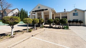 A Georgian-style building with a symmetrical facade, a central entrance with columns, and a sign above the entrance. - Albury Georgian Motel & Suites (Albury)