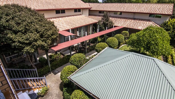 A multi-story building with a red-tiled roof, surrounded by well-maintained greenery and a covered walkway. - Albury Georgian Motel & Suites (Albury)