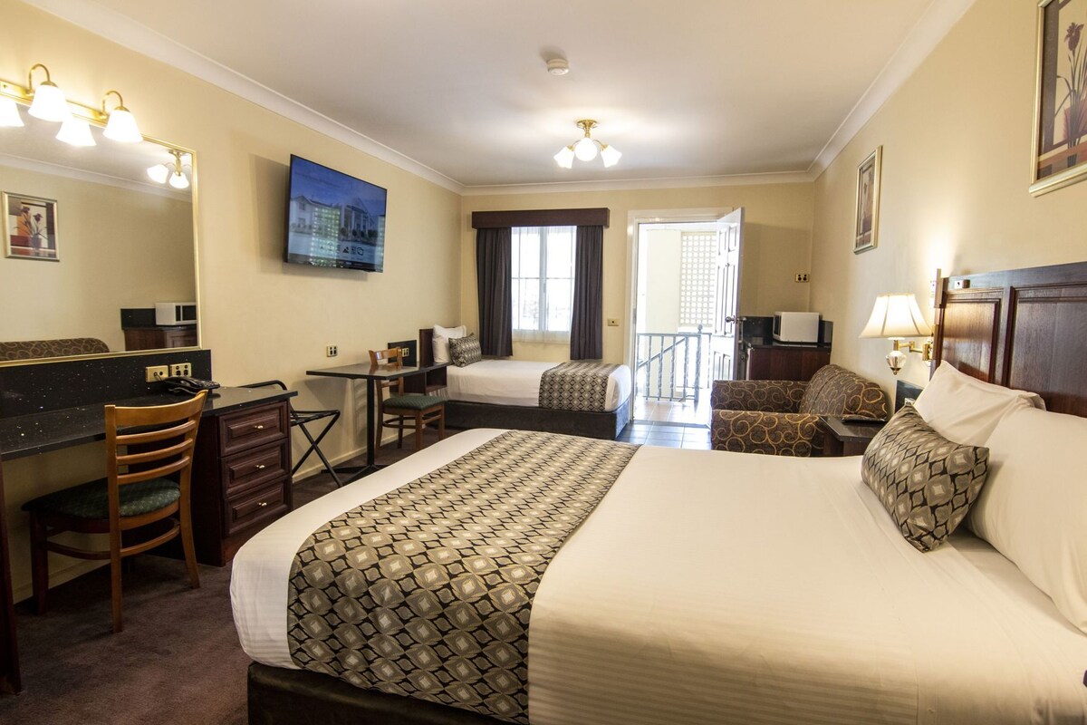 A hotel room with a bed, desk, chair, and a television.
