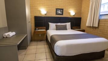 Habitación de hotel con una cama grande, dos mesitas de noche, un cabecero y un cuadro en la pared.