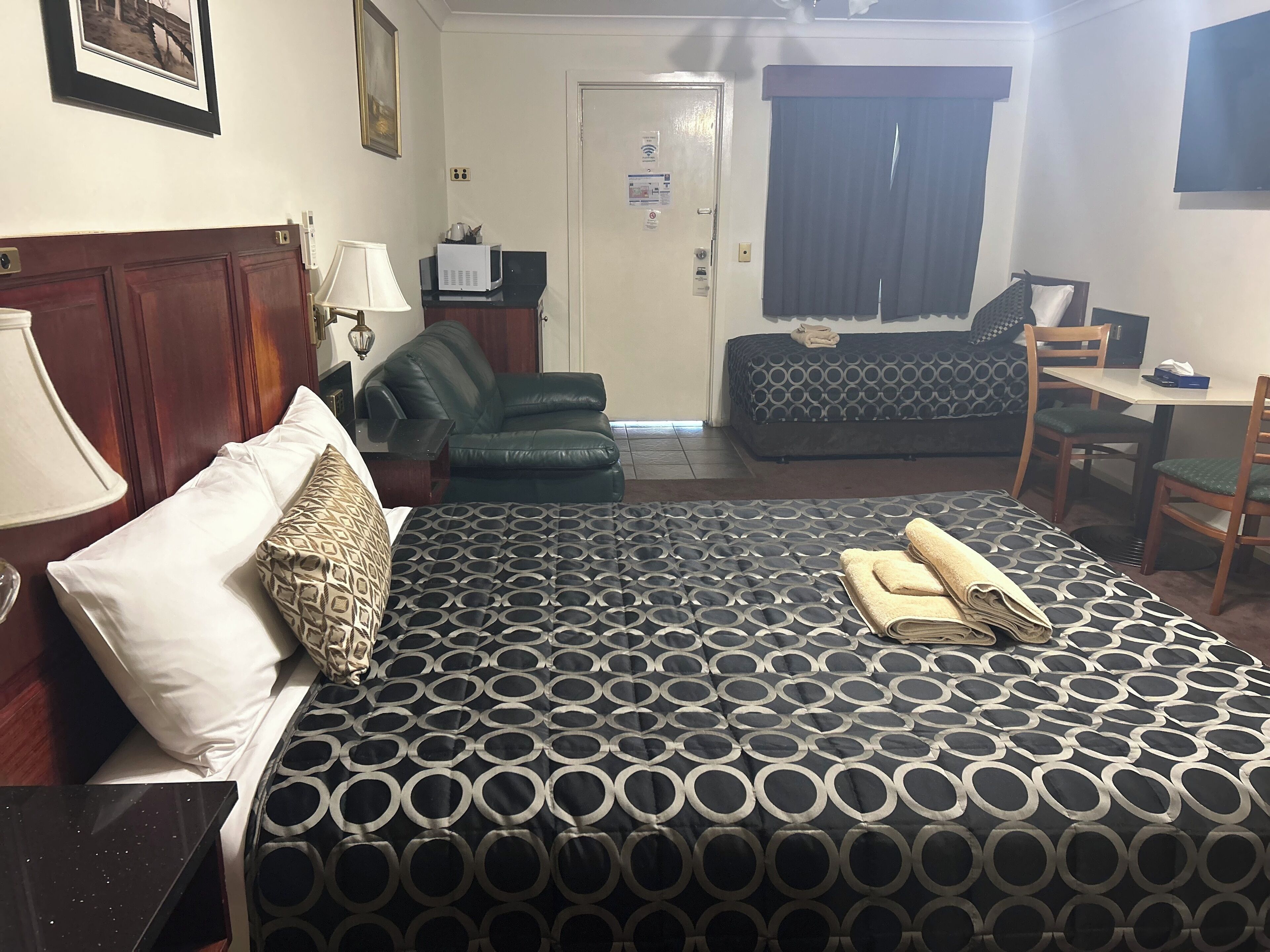 A hotel room with a bed, a desk, a chair, a sofa, and a television.