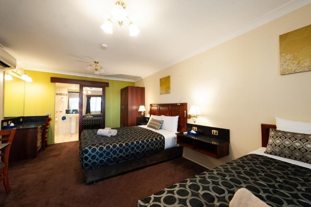 Ein Hotelzimmer mit zwei Betten, einem Schreibtisch und einer Küchenzeile.