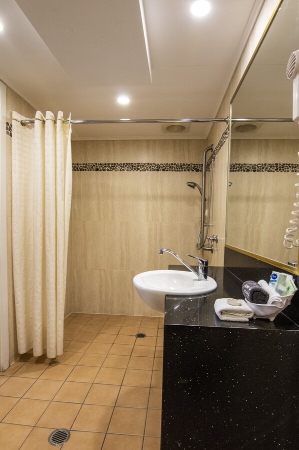A bathroom with a sink, mirror, shower, and towel rack.