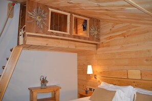 A wooden cabin interior with a bed, a small table with a plant, and a window with a view. - Hotel Coma Bella (Sant Julia de Loria)