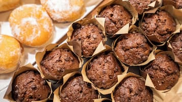 Una bandeja con varios productos horneados, como muffins de chips de chocolate y donas con azúcar glas.