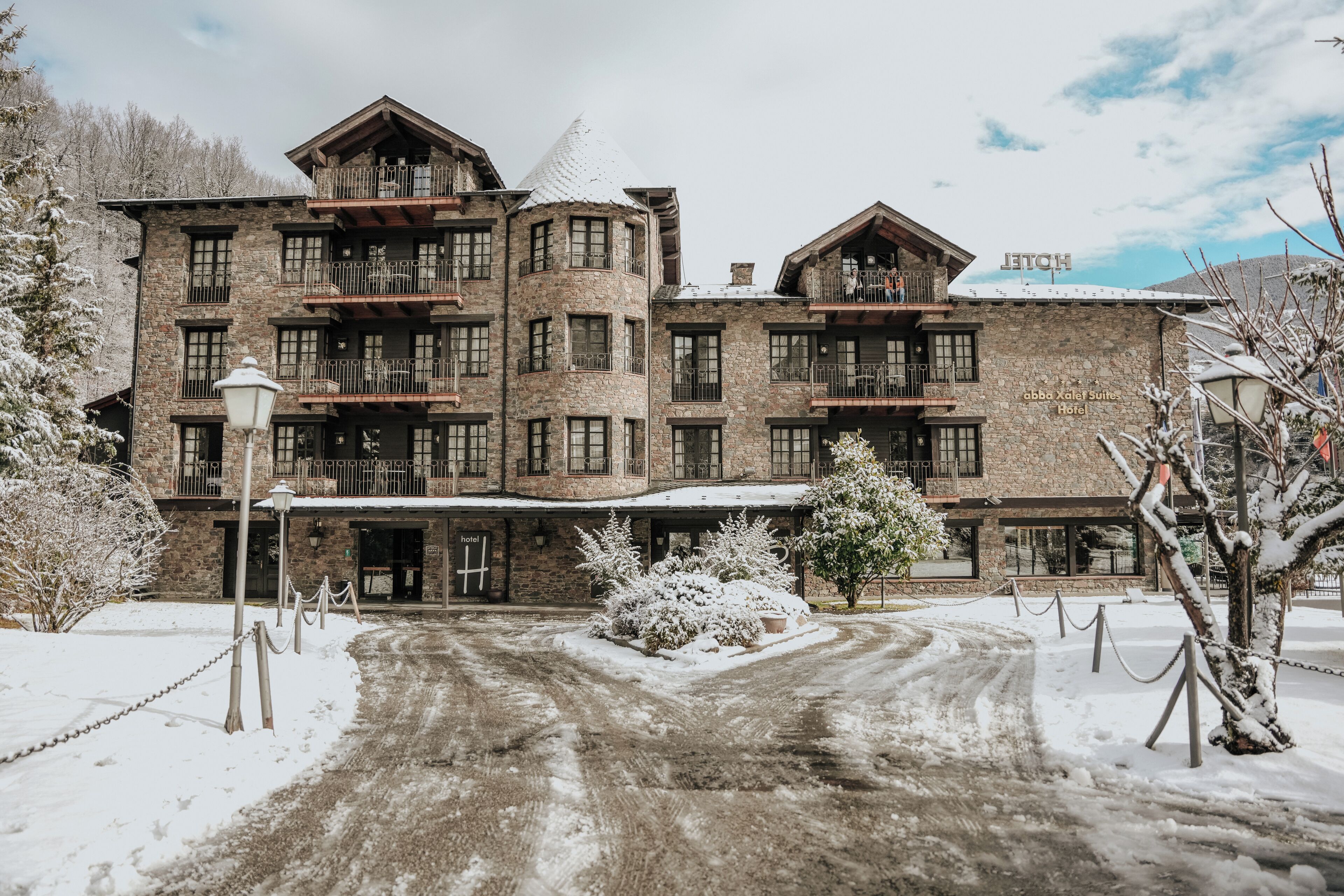 A large, multi-story hotel with a stone facade, multiple balconies, and a snow-covered entrance.