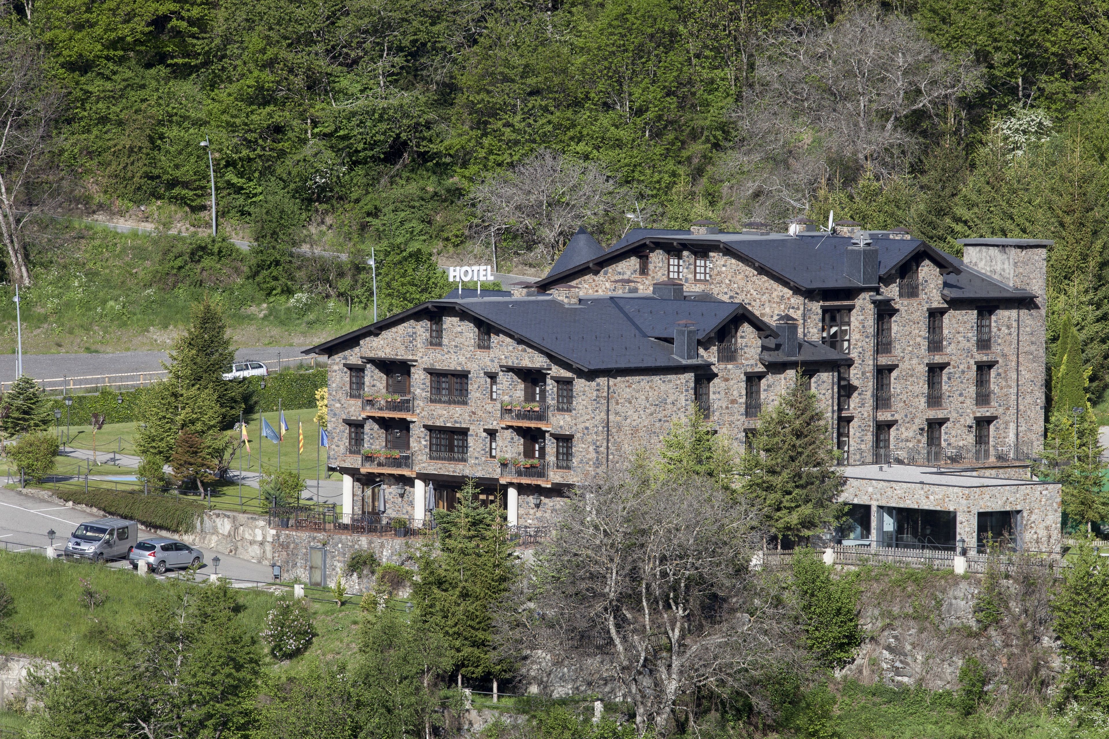 A multi-story hotel with a stone facade, balconies, and a sign indicating it is a hotel.