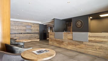 A modern reception area with a wooden reception desk, leather seating, and a round table with a magazine.