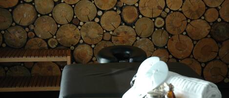 Zona de spa con pared de madera, una camilla de masaje y una toalla.
