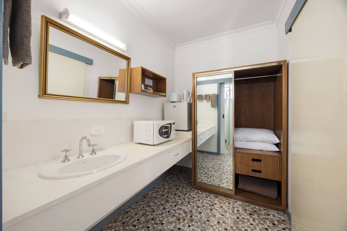 A bathroom with a sink, mirror, and a walk-in closet with a mirror.