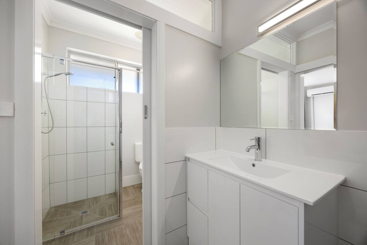 A modern bathroom with a glass-enclosed shower, a white sink, and a large mirror.