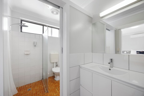 A modern bathroom with a shower, toilet, and sink.