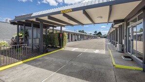 A hotel entrance with a covered walkway, directional arrows on the pavement, and a clear sky. - Castle Motel Bairnsdale (Bairnsdale)