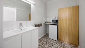 A modern bathroom with a white sink, mirror, and wooden wardrobe. - Castle Motel Bairnsdale (Bairnsdale)
