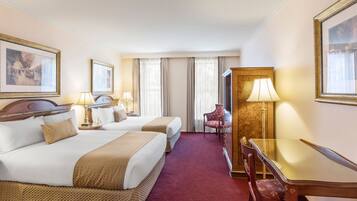 A hotel room with two beds, a desk, and a chair.