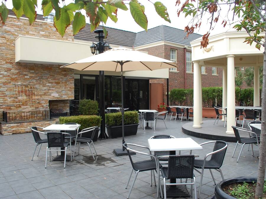 An outdoor patio area with tables and chairs, a brick wall, and a covered seating area.