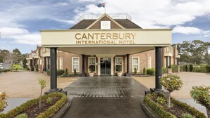 Canterbury International Hotel with a prominent entrance, a flag on top, and a brick facade. - Canterbury International Hotel (Forest Hill)