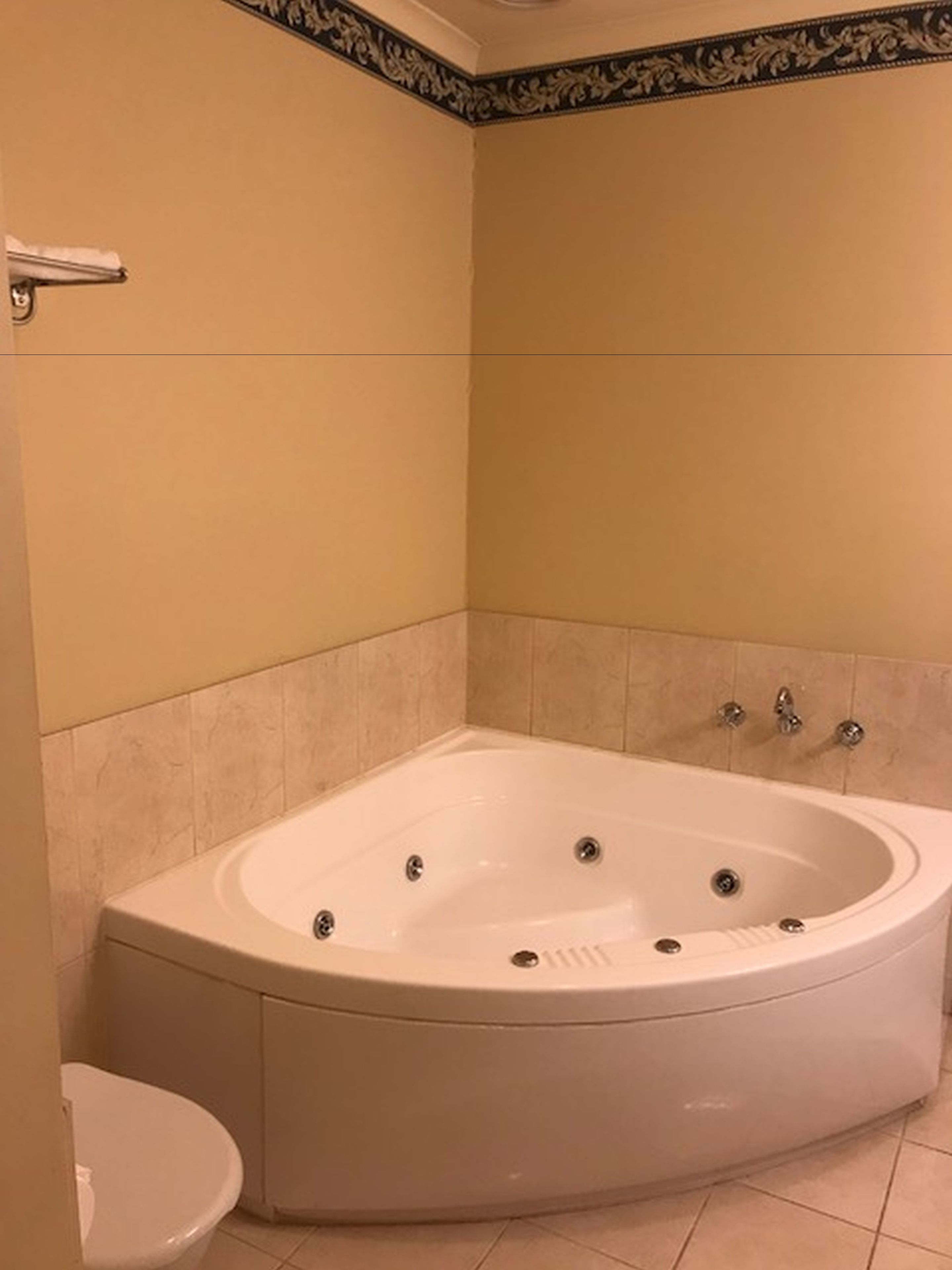 A bathroom with a freestanding bathtub, a toilet, and tiled walls.