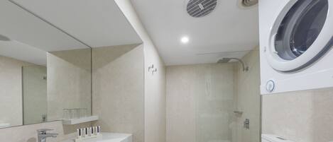 Un baño moderno con un espejo grande, dos lavamanos, un inodoro y una lavadora integrada.