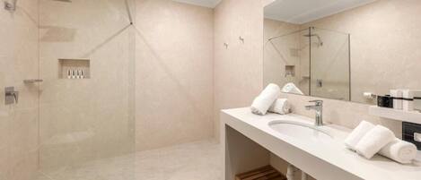 Un baño moderno con ducha envuelta en vidrio, un espejo grande y un mueble de tocador de madera.
