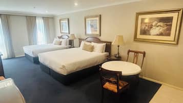 Une chambre d’hôtel avec deux lits, une table ronde, une chaise et une lampe.