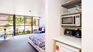 A modern room with a bed, a small seating area, and a kitchenette with a microwave and toaster. - Lorne Bay View Motel (Lorne)