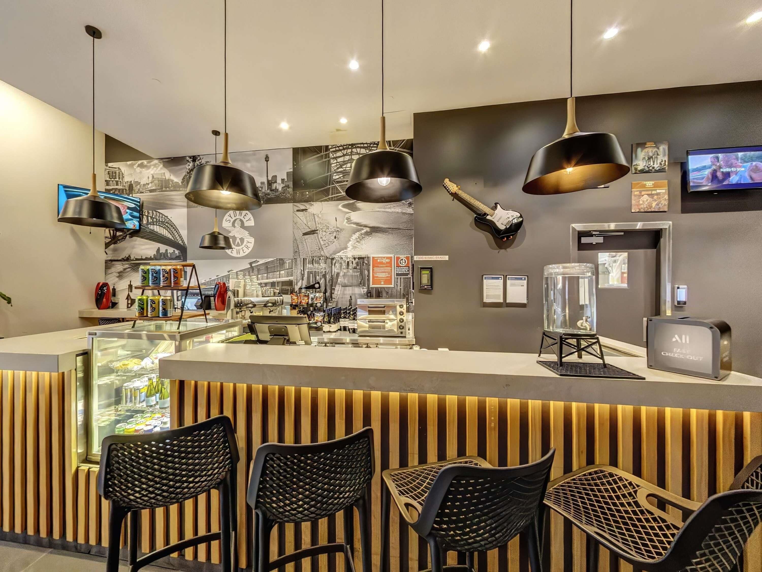 A modern bar area with a counter, black chairs, and a guitar on the wall.