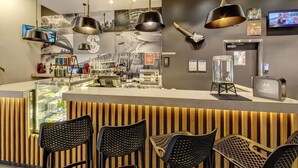 Una zona de bar moderna con una barra, sillas negras y una guitarra en la pared.