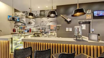 A modern bar area with a counter, black chairs, and a guitar on the wall.