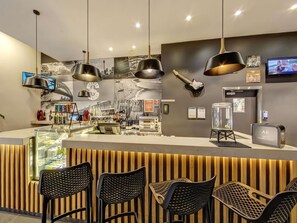 Una zona de bar moderna con una barra, sillas negras y una guitarra en la pared.