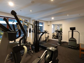 A gym with various exercise equipment, large windows, and a mirror. - ibis Sydney World Square (Sydney)