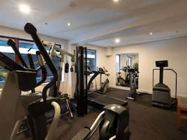 A gym with various exercise equipment, large windows, and a mirror.