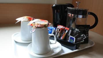 Una bandeja con dos tazas blancas, una cafetera y varios pods de café.