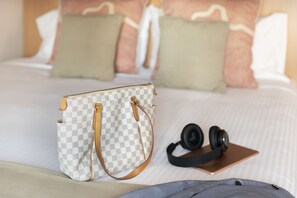 A bed with pillows, a checkered bag, headphones, and a tablet. - ibis Sydney World Square (Sydney)