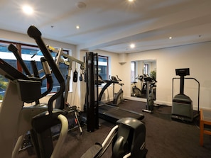 Un gimnasio con equipo de ejercicio, ventanas amplias y un espejo.