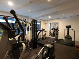 A gym with exercise equipment, large windows, and a mirror.